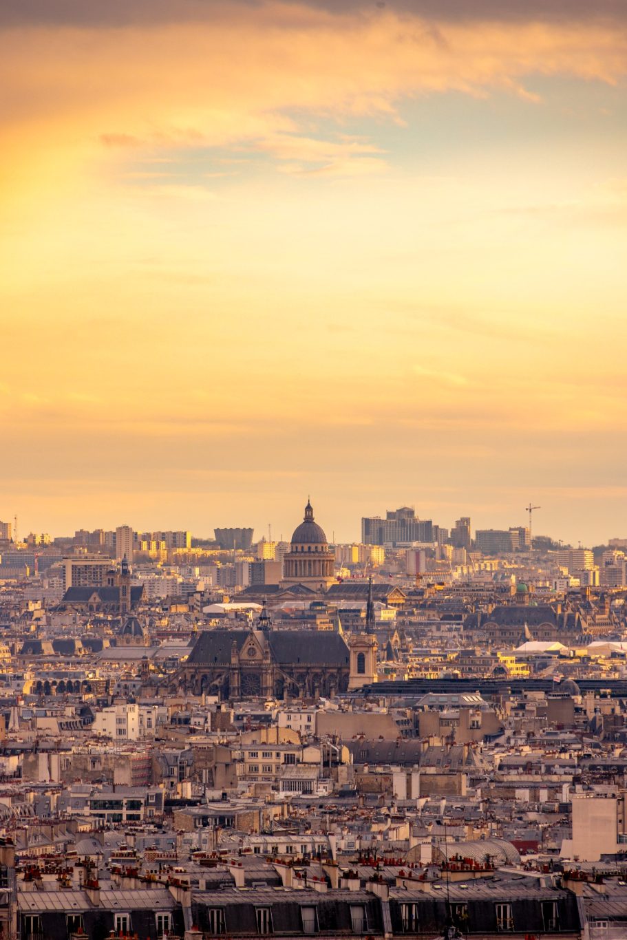 View of a cityscape at sunset with a dome in the background.
