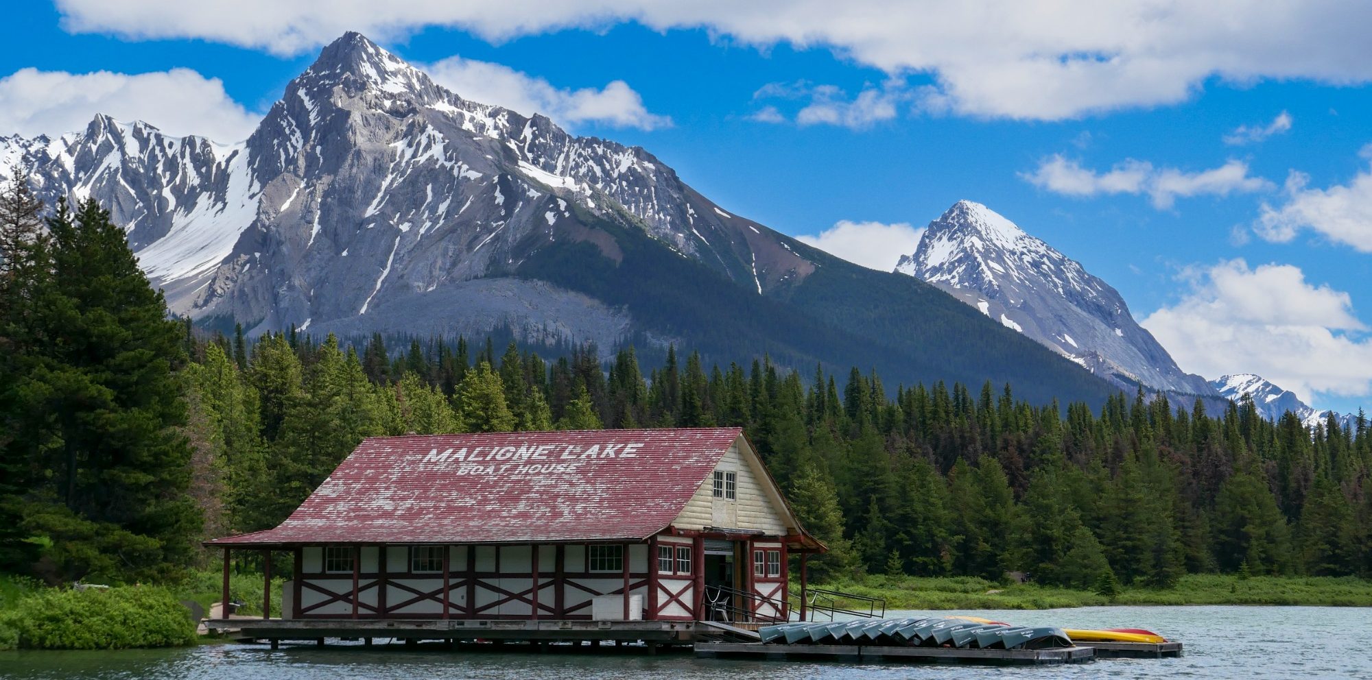 Where Mountains Meet the Water A wooden house by the water with snow-capped mountains in t