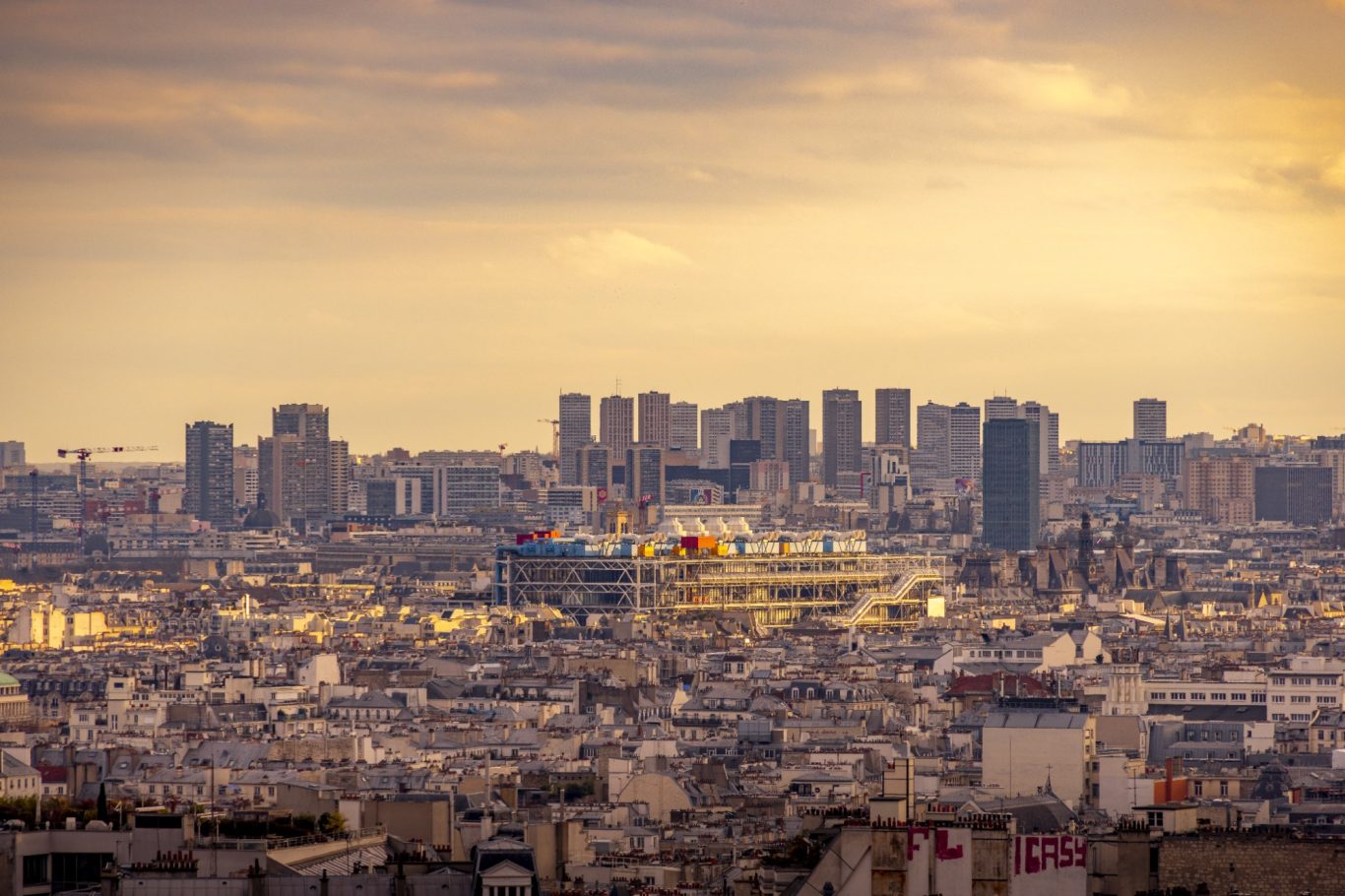 City view at sunset with buildings and a stadium in the foreground.