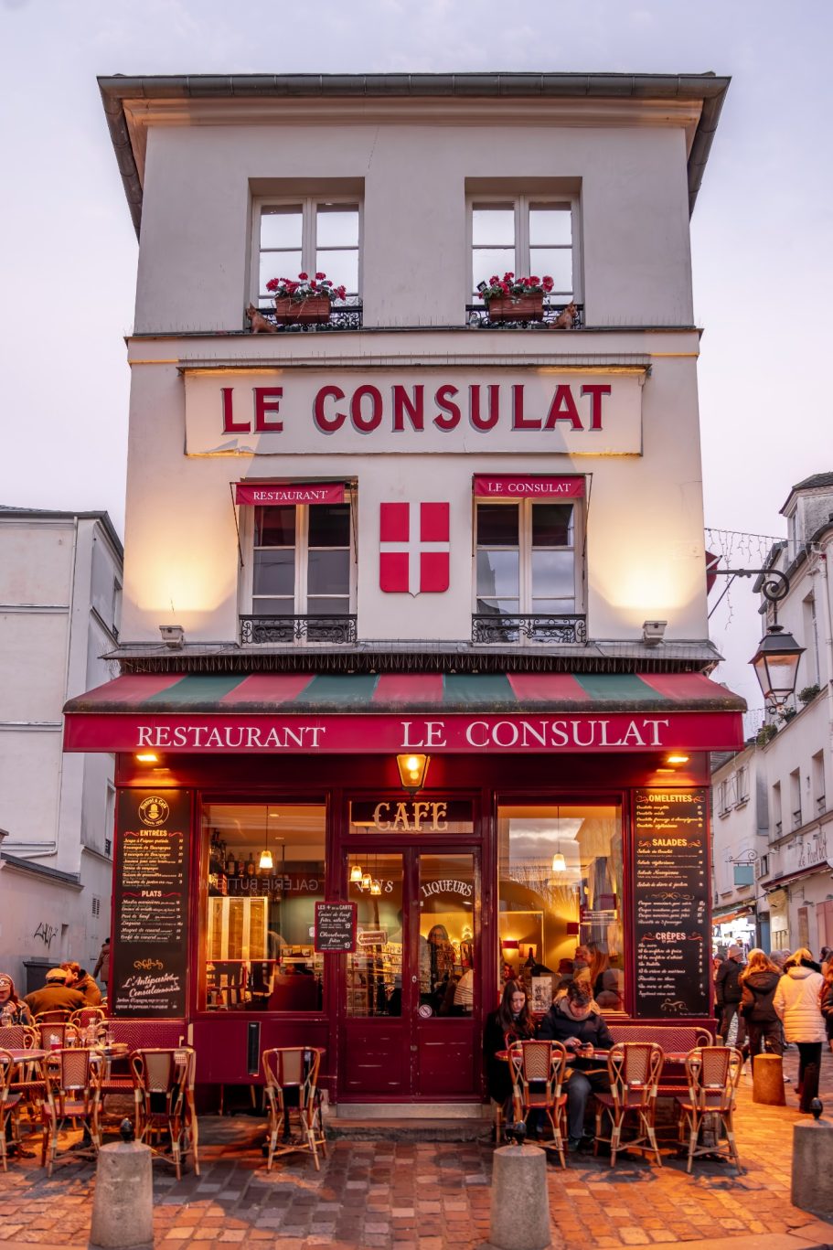 Restaurant "Le Consulat" with red sign and outdoor tables