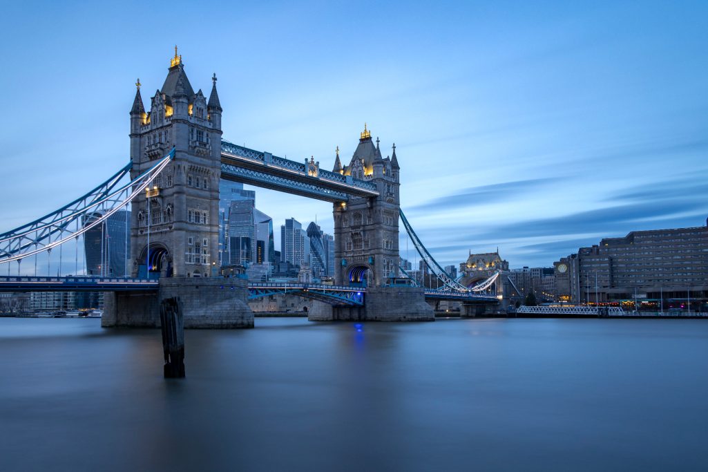 The Tower Bridge in London at dusk with reflective water in the foreground.