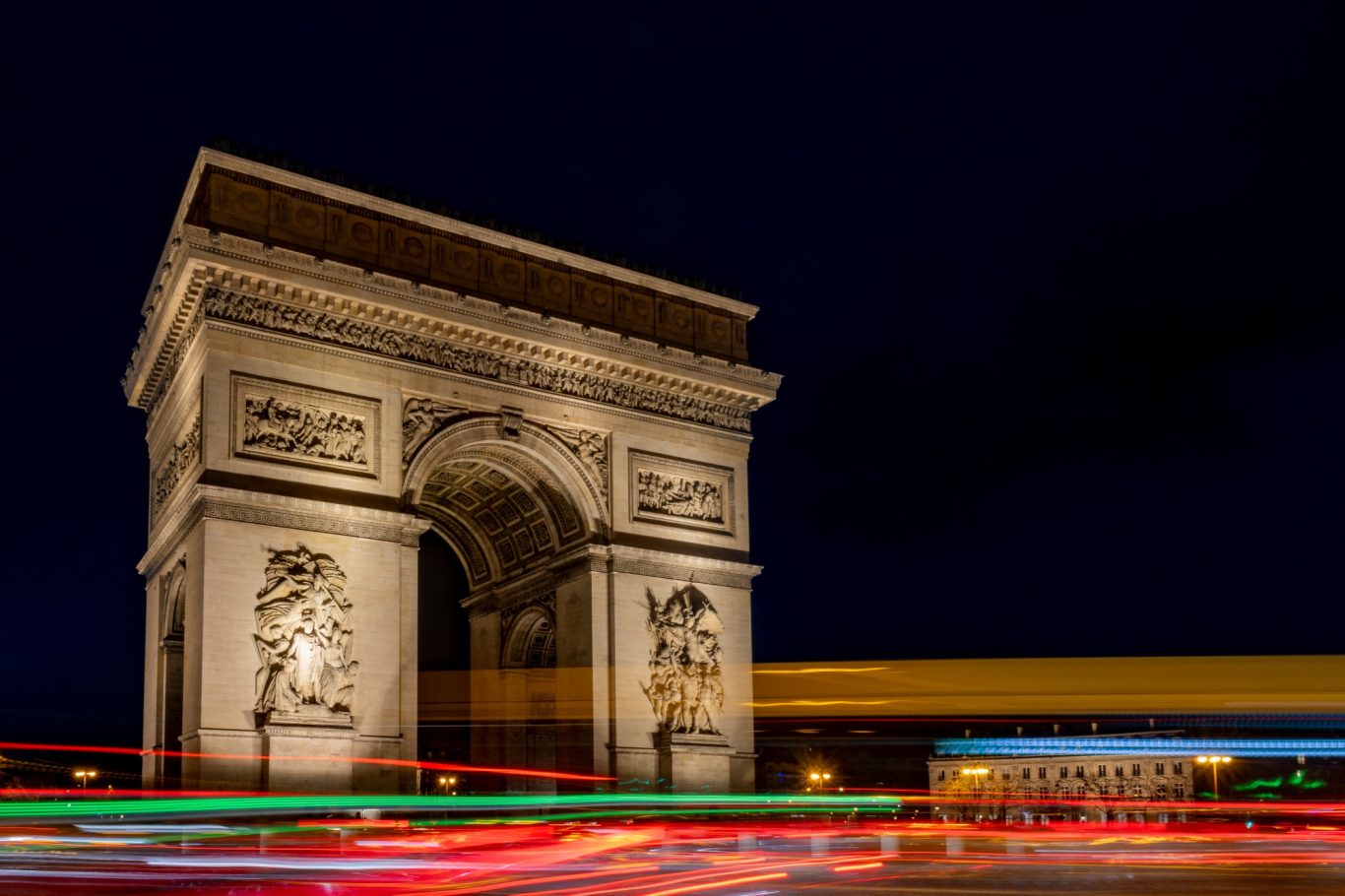 The Arc de Triomphe at night with blurred lights in the foreground.